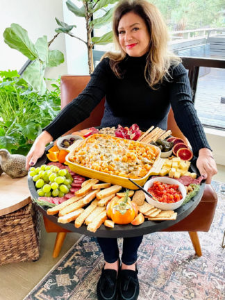 woman holding a Friendsgiving Pasta Bake Board with 9x13 pan in center