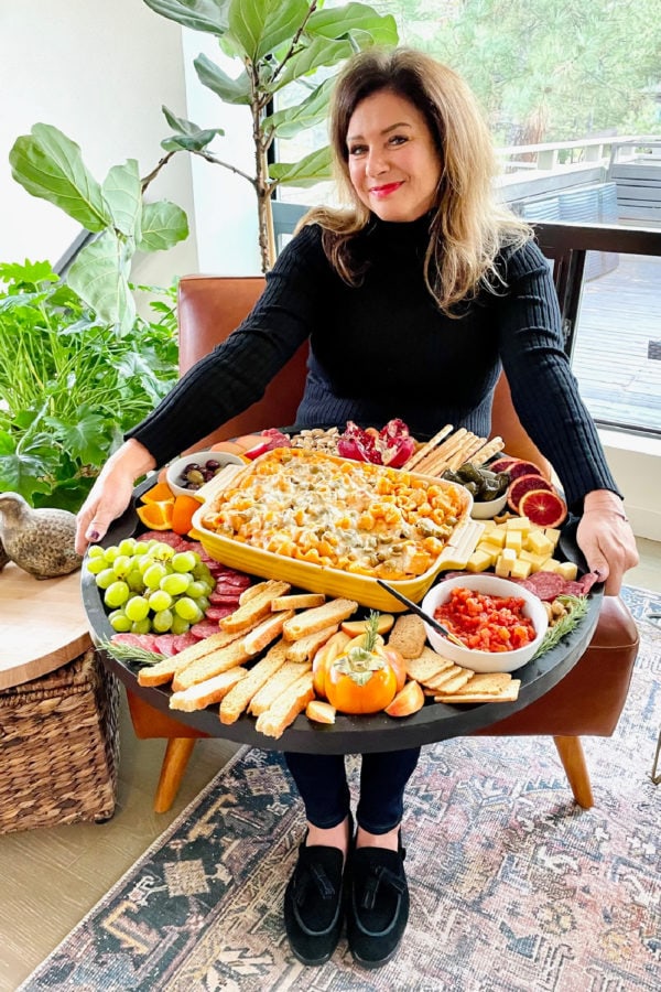 woman holding a Friendsgiving Pasta Bake Board with 9x13 pan in center