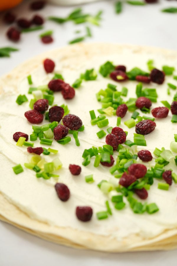 spreading cream cheese on Orange Cranberry Pinwheels Appetizer