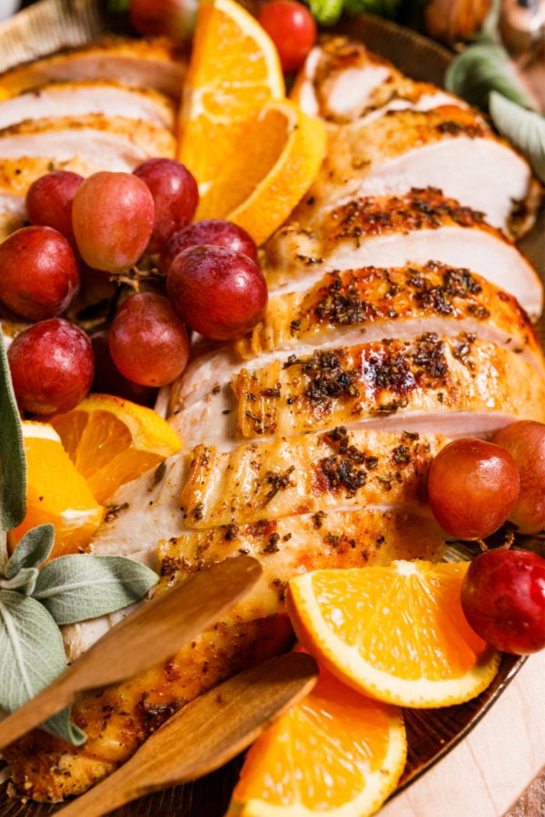 slices of Orange Spiced Spatchcocked Turkey with oranges and grapes garnish