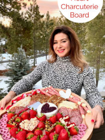 a woman holding a round Brie-Filled Heart Charcuterie Board