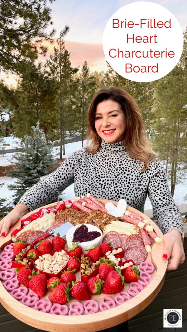a woman holding a round Brie-Filled Heart Charcuterie Board