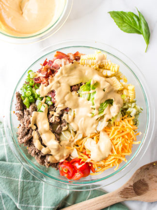 adding dressing to Bacon Cheeseburger Pasta Salad