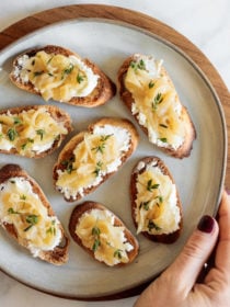 bite of Caramelized Onion Crostini with goat cheese and fresh thyme