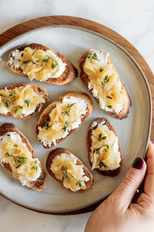 bite of Caramelized Onion Crostini with goat cheese and fresh thyme