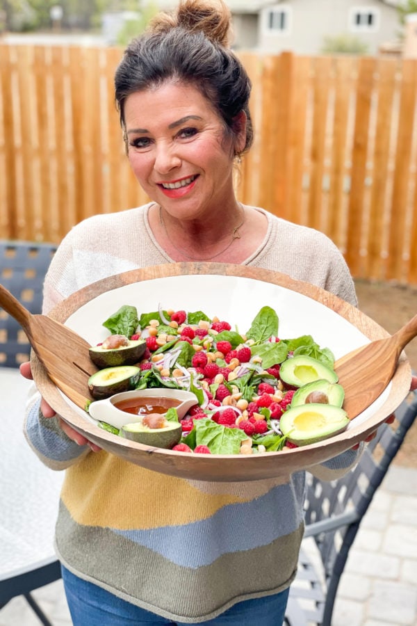 a woman holding an epic Spinach Raspberry Salad