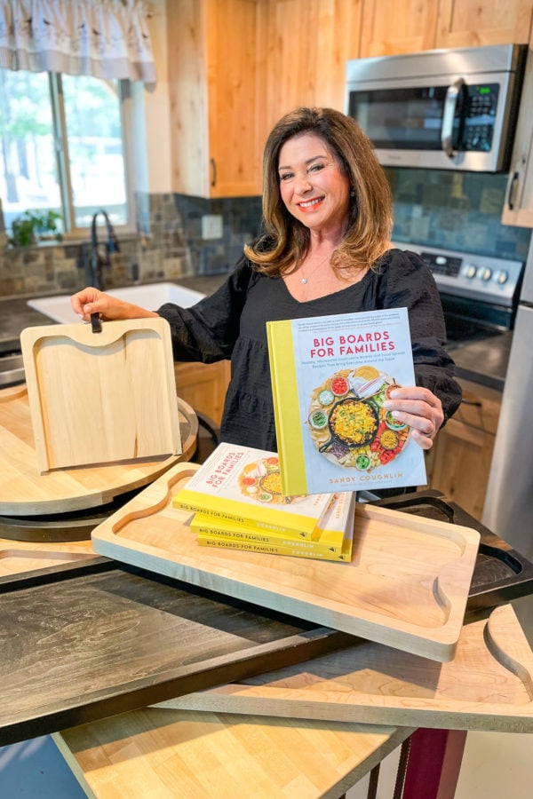 woman holding a cookbook and charcuterie boards