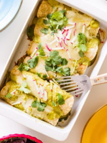 serving a pan of Cheesy Seafood Green Enchiladas