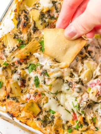 dipping pita chips into Green chili Artichoke Dip