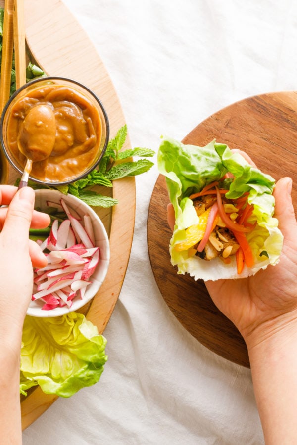 adding peanut sauce to a chicken wrap