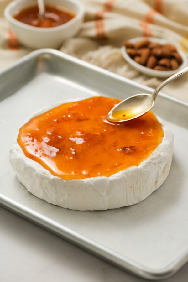 spreading peach jam on brie