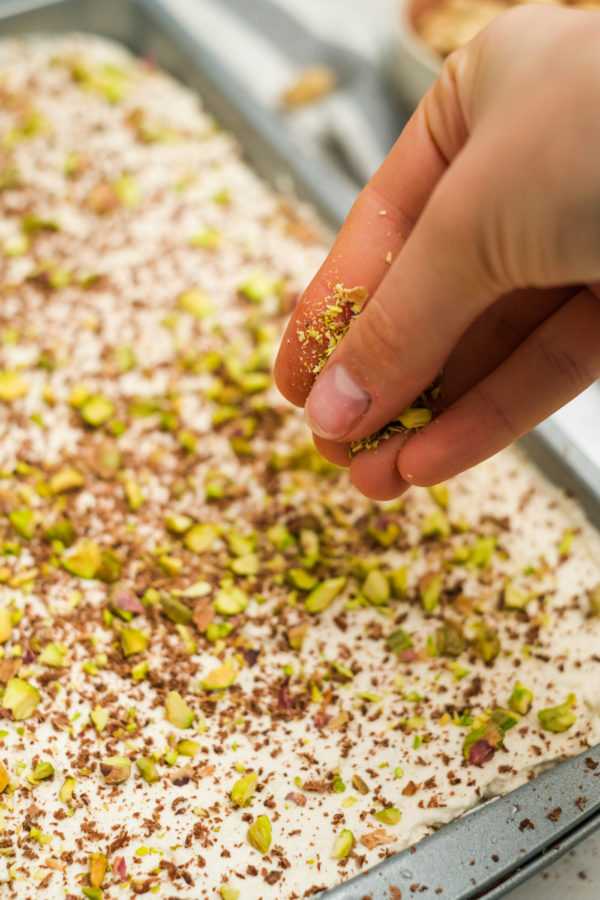 sprinkling pistachios on a cake