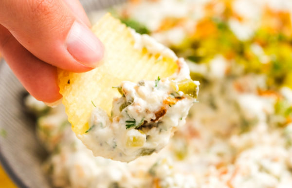 taking a bite of dill pickle fried onion dip