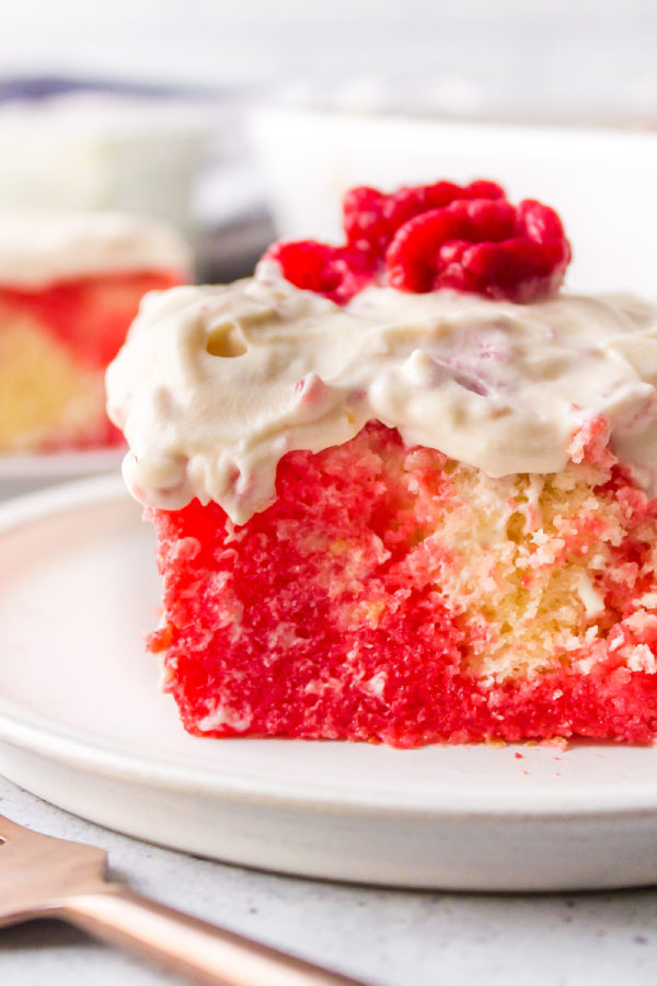 raspberry jello cake serving with whipped cream