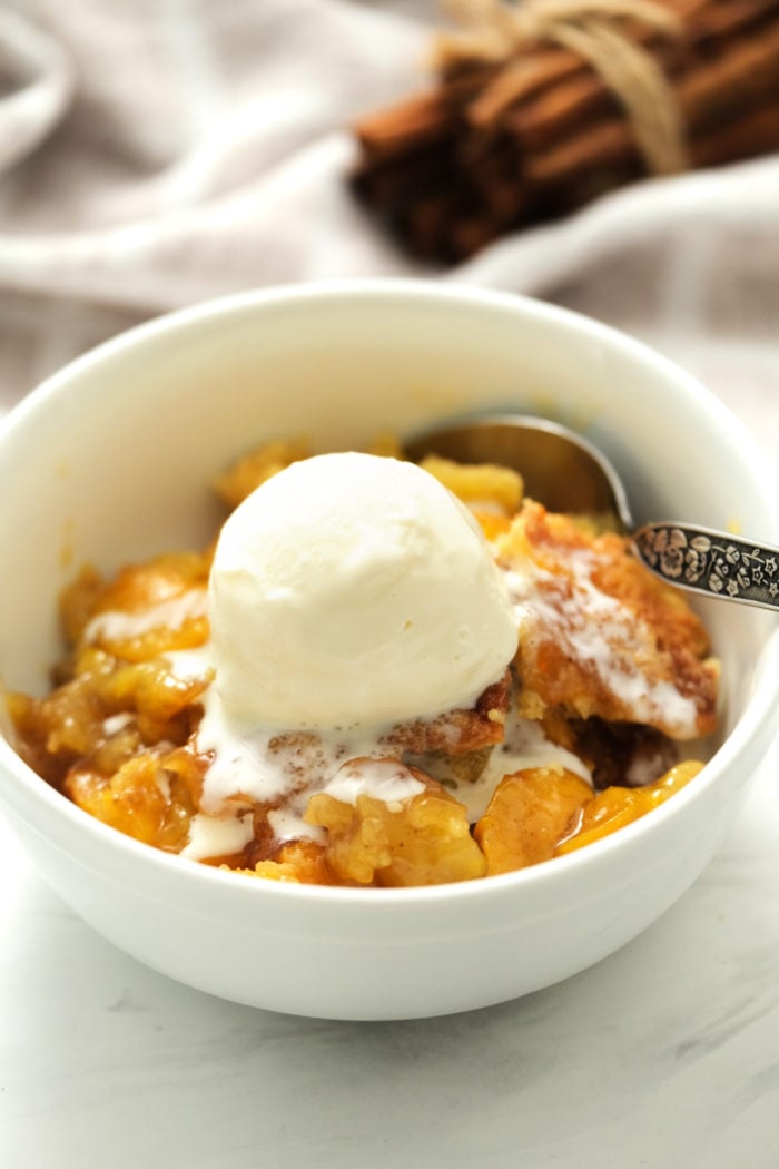 a bowl of cobbler with peaches and ice cream