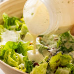 pouring Pineapple Dressing over lettuce
