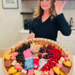 woman holding a cherry and Valentine dessert board