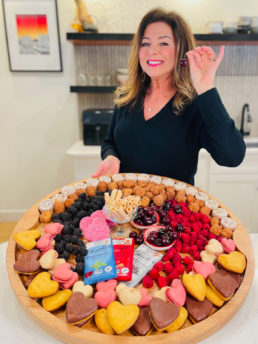 woman holding a cherry and Valentine dessert board