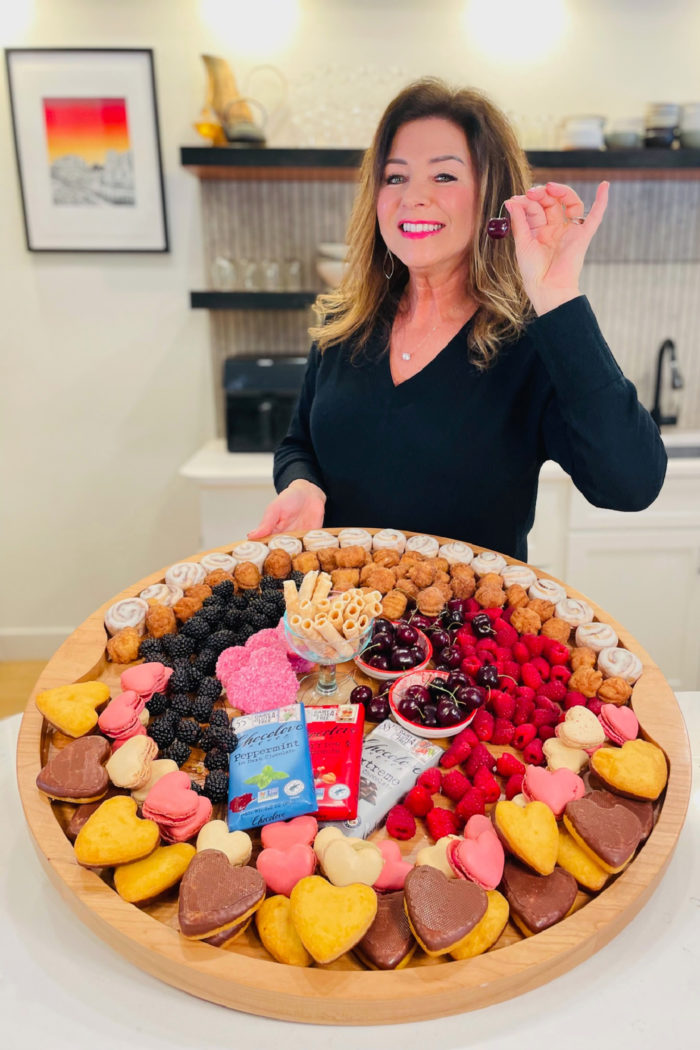 woman holding a cherry and Valentine dessert board