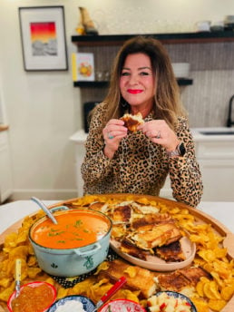 tomato soup board with woman taking bite grilled cheese