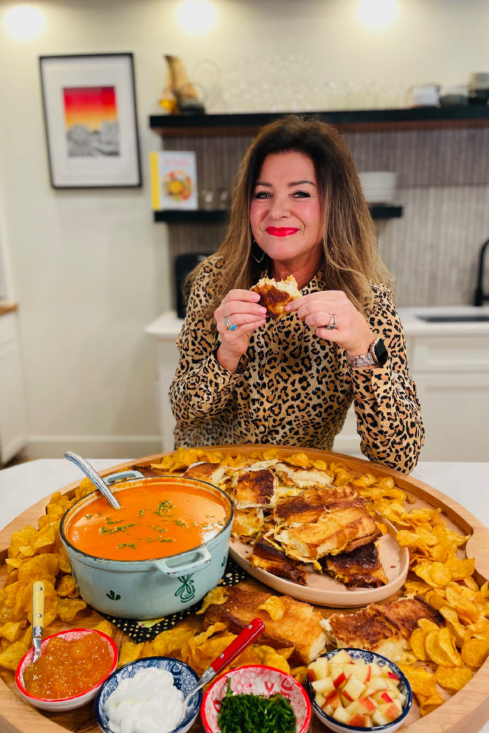 tomato soup board with woman taking bite grilled cheese