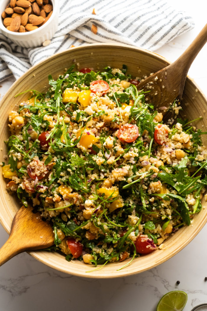 tossing an arugula salad with veggies and cheese