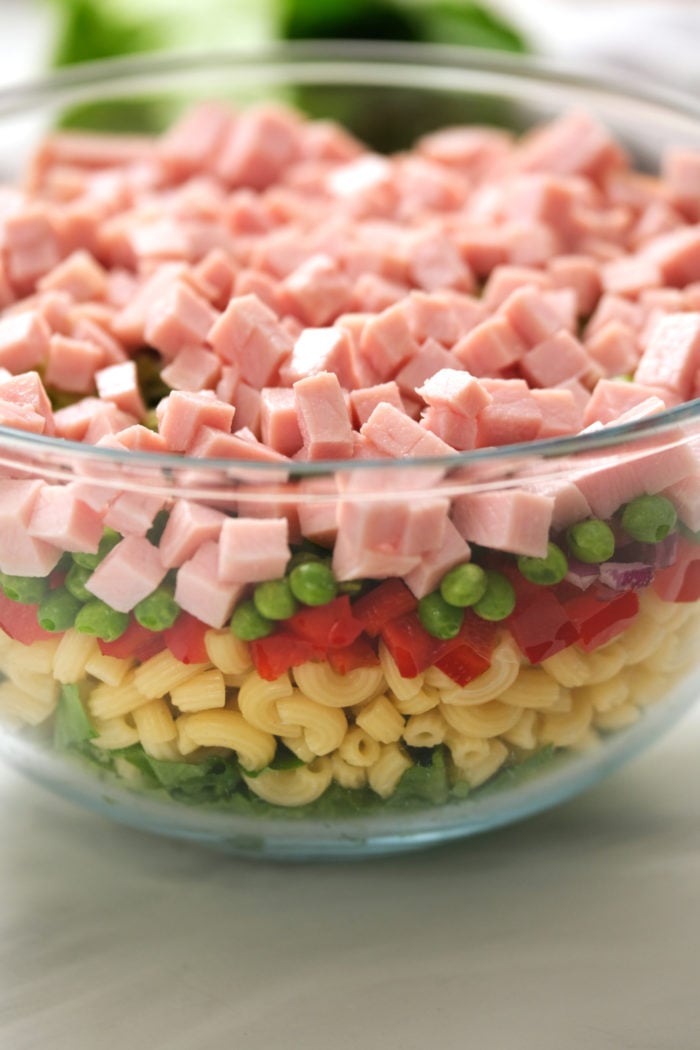 layering a pasta salad with ham and peas