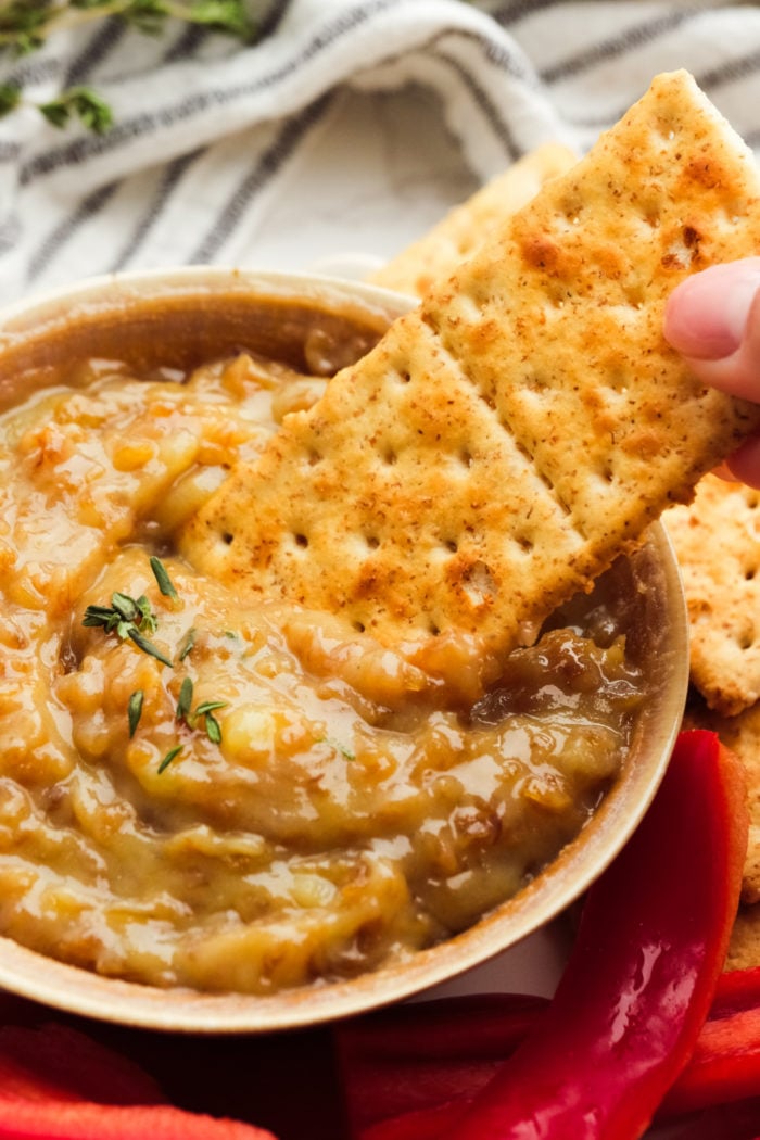 dipping a cracker into onion butter