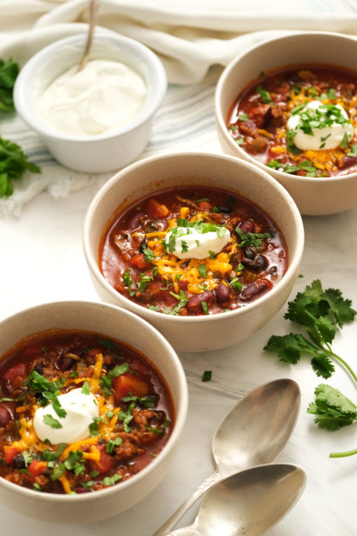 3 bowls of chili garnished with sour cream