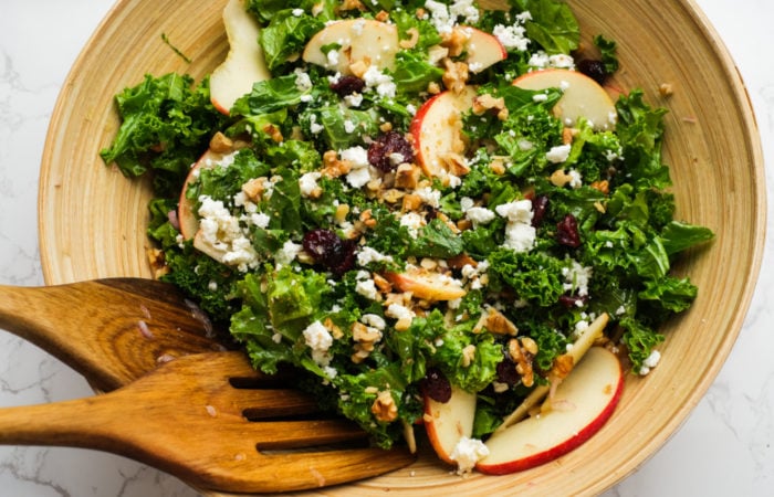 tossing a kale salad with apples