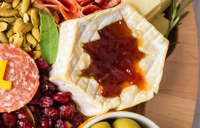 wheel of cheese with a leaf cut-out filled with jam