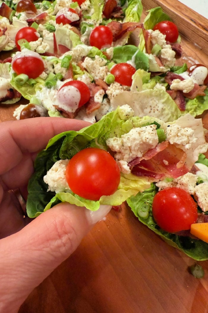 holding a BLT lettuce cup