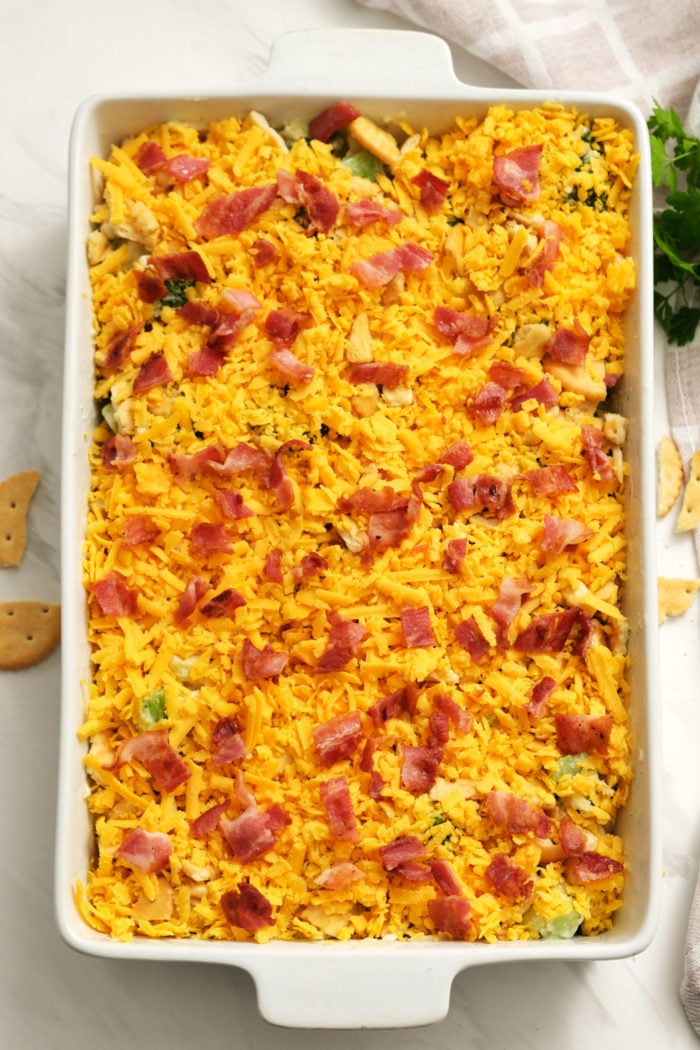 adding cheese and bacon to casserole