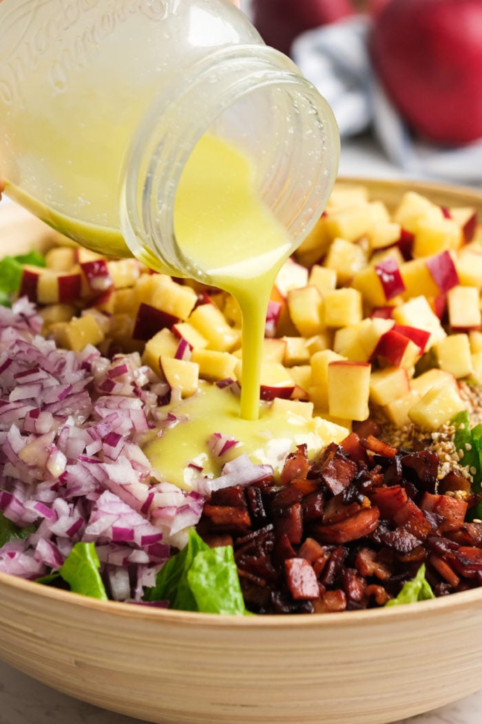 pouring a yellow dressing over lettuce