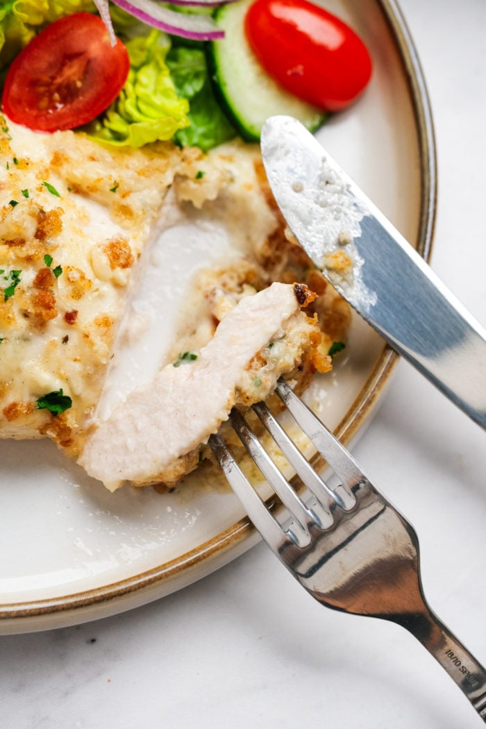 cutting a piece of chicken with knife and fork