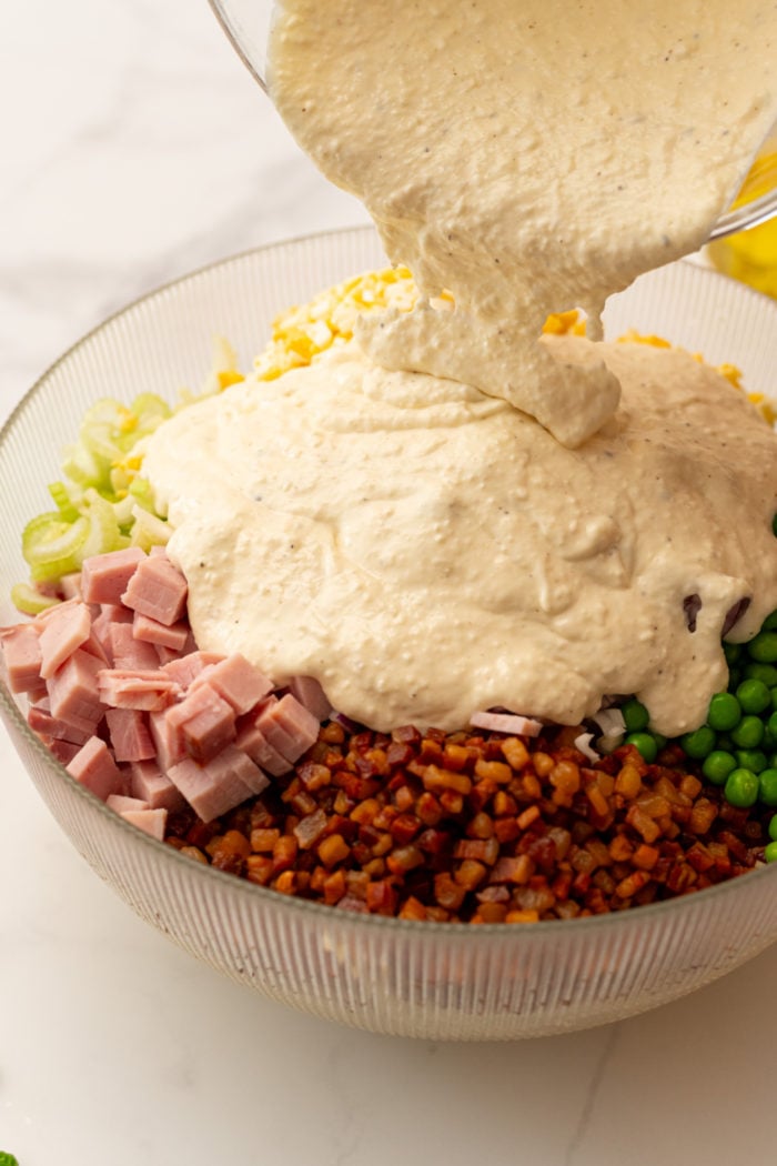 pouring dressing over pasta salad