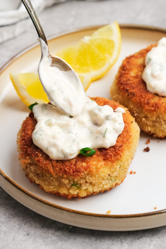 adding tartar sauce to a fish cake