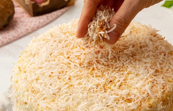 sprinkling toasted coconut on a cake