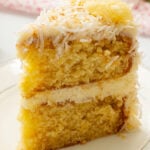 Slice of cake with frosting and pineapple and coconut on top