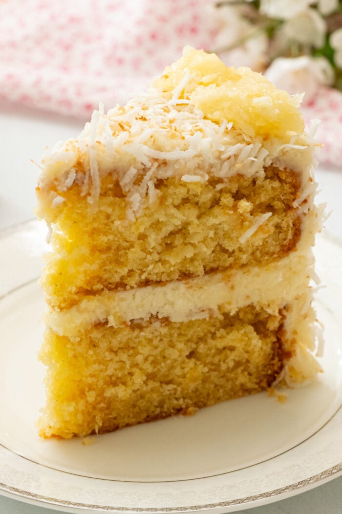 Slice of cake with frosting and pineapple and coconut on top