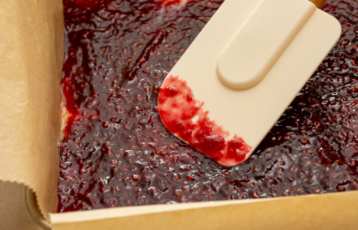 spreading raspberry jam on bars