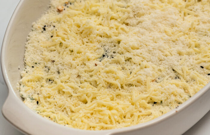 adding grated cheese to a dip
