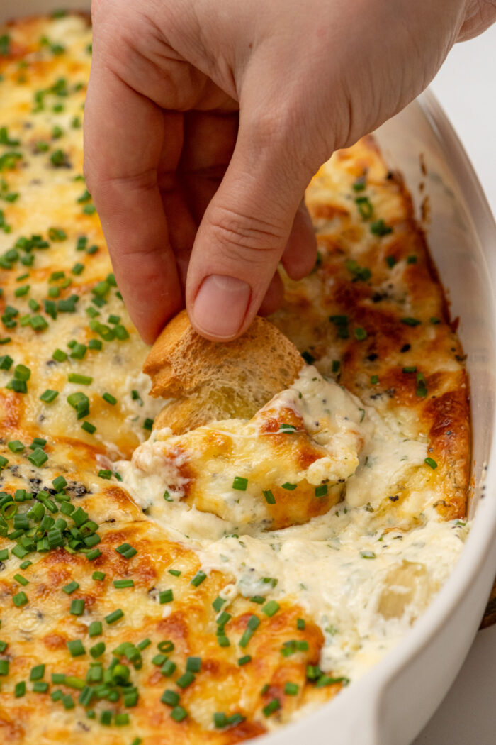 dipping crostini in a garlic dip