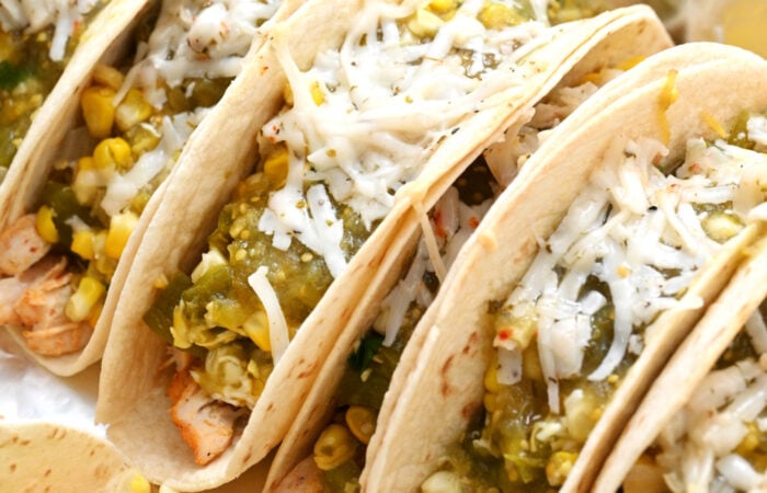 adding green sauce and cheese to a taco