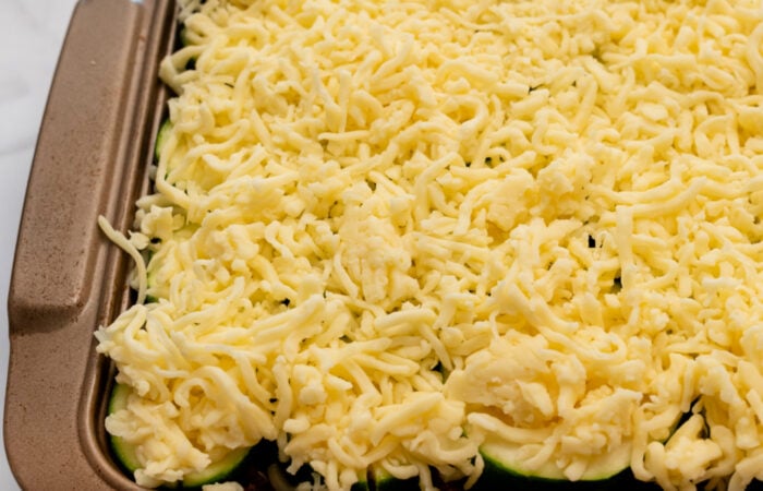 preparing zucchini casserole with grated cheese