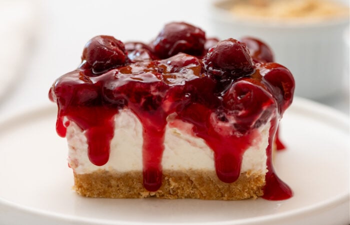 cherries dripping down over a piece of cheesecake
