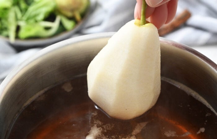 adding a pear to sauce to poach it