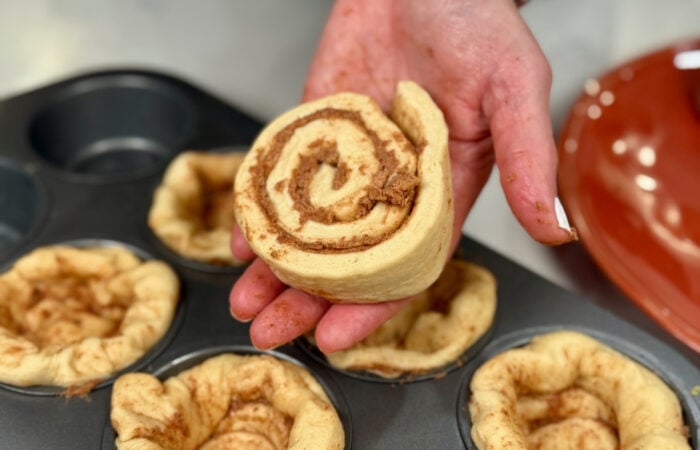 placing canned cinnamon rolls in a muffin tin