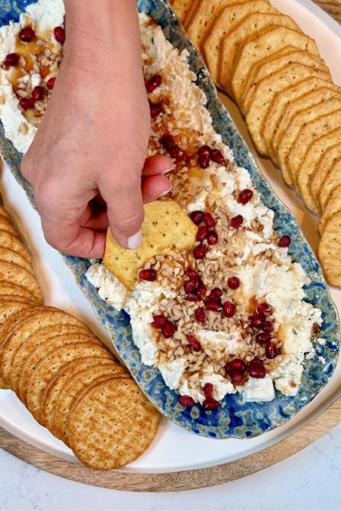 dipping a cracker into cheese spread