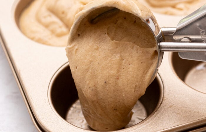 scooping applesauce muffins to a pan